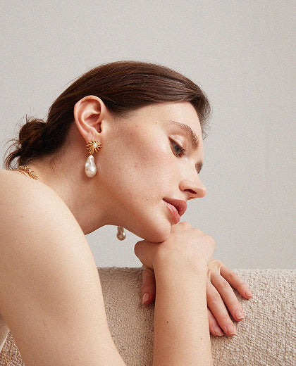 Woman wearing pearl earrings with a neutral background