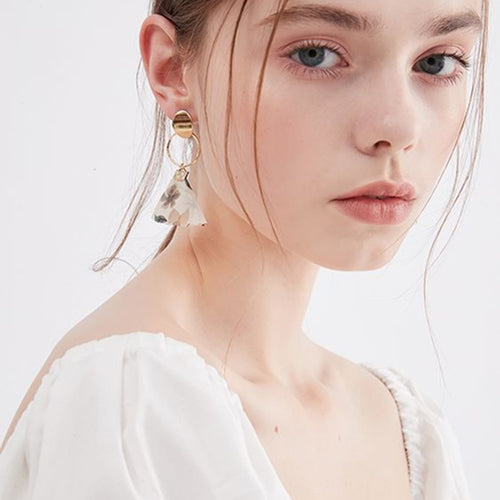 Close up of a person wearing gold hoop earrings with a white background